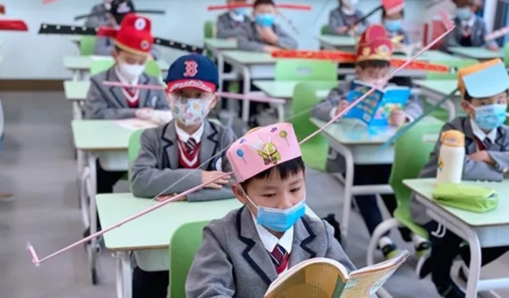 Students use special hats to keep social distancing in China