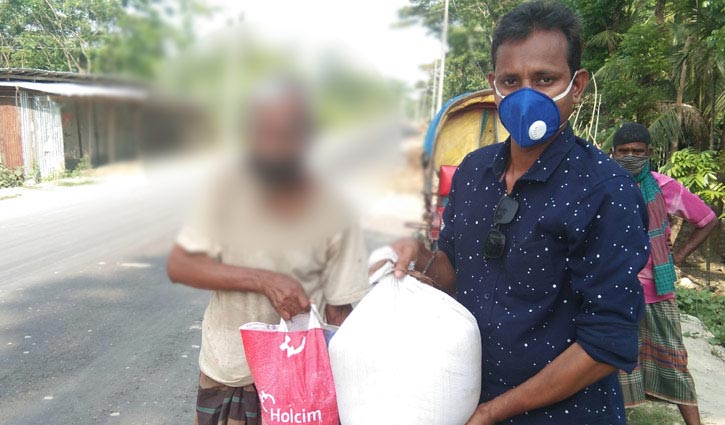 Uday Hakim stands with food assistance by Barguna elderly man